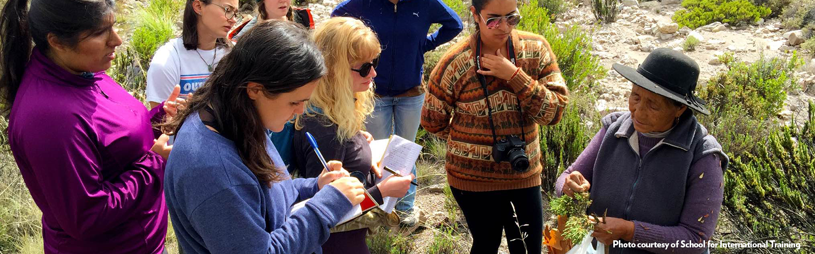 Students are conducting research on plants outside. They are being led by a local community member.